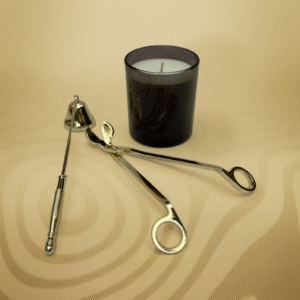 ALKIDO gold candle care tools — wick trimmer and snuffer — displayed next to a black glass soy candle on a warm beige background.