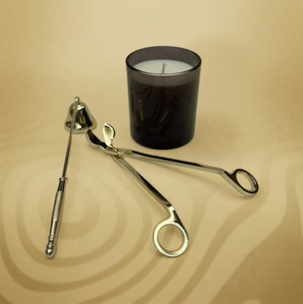 ALKIDO gold candle care tools — wick trimmer and snuffer — displayed next to a black glass soy candle on a warm beige background.