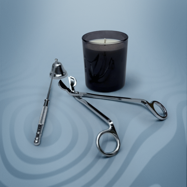 ALKIDO silver candle care tools — wick trimmer and snuffer — arranged beside a black glass soy candle on a cool blue background.
