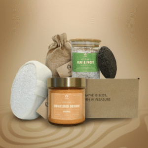 ALKIDO spa gift set featuring 'Sunkissed Desire' orange body scrub, 'Leaf & Frost' Dead Sea salt spa mix with eucalyptus, lavender sachet in linen bag, white natural loofah, black lava stone, and kraft box with brand message, on a warm beige background.