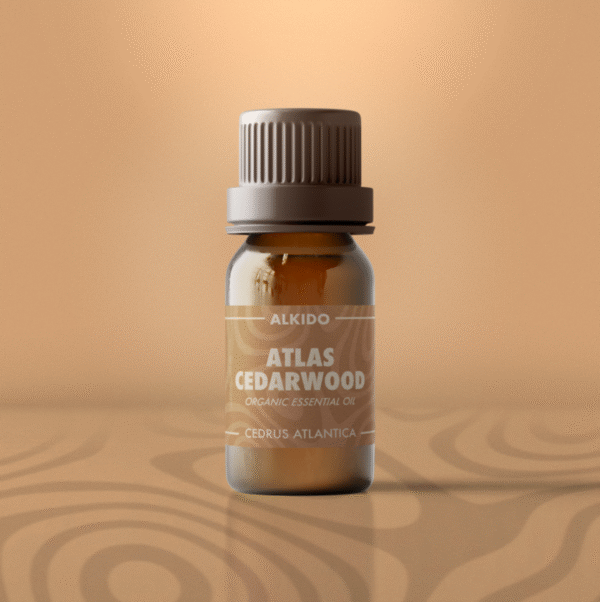 ALKIDO Atlas Cedarwood Organic Essential Oil in amber 10ml bottle with warm tan label on muted sand background.