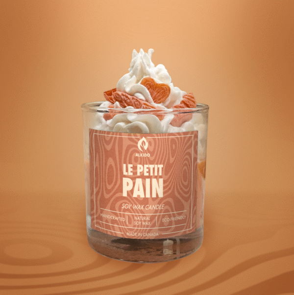 ALKIDO LE PETIT PAIN soy wax candle in a dessert style glass with whipped wax and sculpted bread topping on a warm orange background