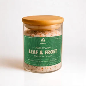 ALKIDO Leaf frost spa salt mix in a clear glass jar with a wooden lid and green label, topped with dried lemon balm, on a light background