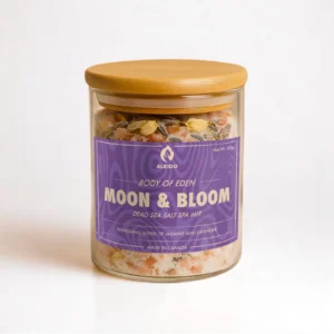 ALKIDO Moon bloom spa salt mix in a clear glass jar with a wooden lid and purple label, topped with dried lavender and jasmine petals, on a light background