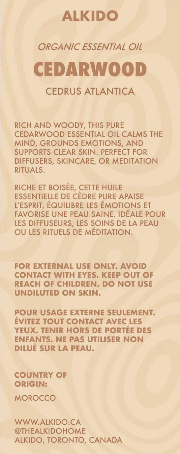 ALKIDO Cedarwood Organic Essential Oil label featuring Cedrus Atlantica. Describes the oil as rich and woody, ideal for calming the mind, grounding emotions, and skincare. Includes bilingual safety warnings and product origin (Morocco). Beige label with earthy brown tones and modern typography.