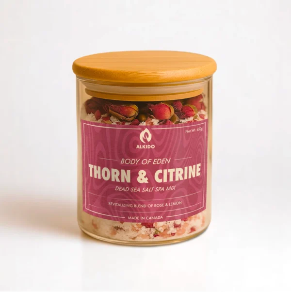 ALKIDO Thorn Citrine spa salt mix in a clear glass jar with a wooden lid and red label, topped with dried rose petals, on a light background