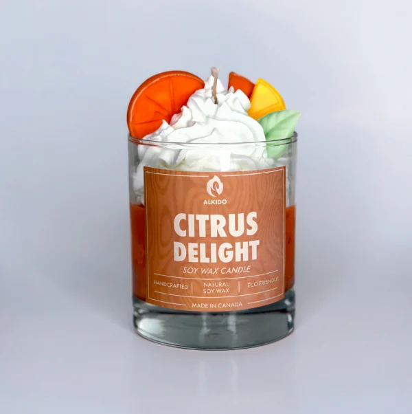 Decorative candle with orange and lemon slices decor on top with a green leaf and an orange label