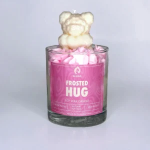 Decorative candle with a bear decor on top and a pink label