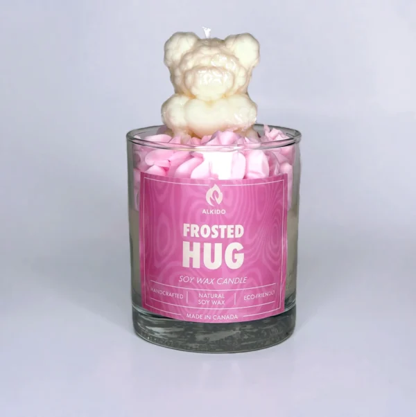 Decorative candle with a bear decor on top and a pink label
